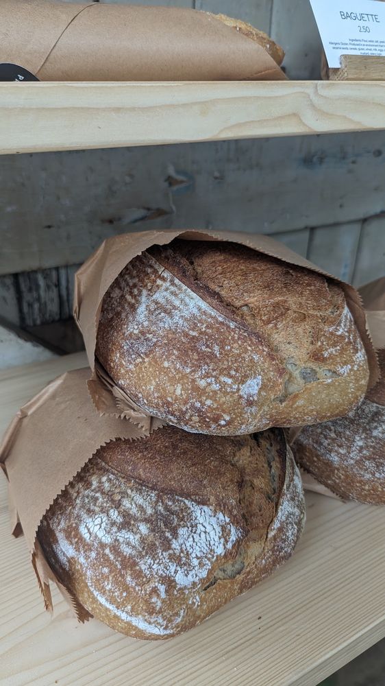 Flour-dusted sourdough loaves stacked in paper on a wooden counter