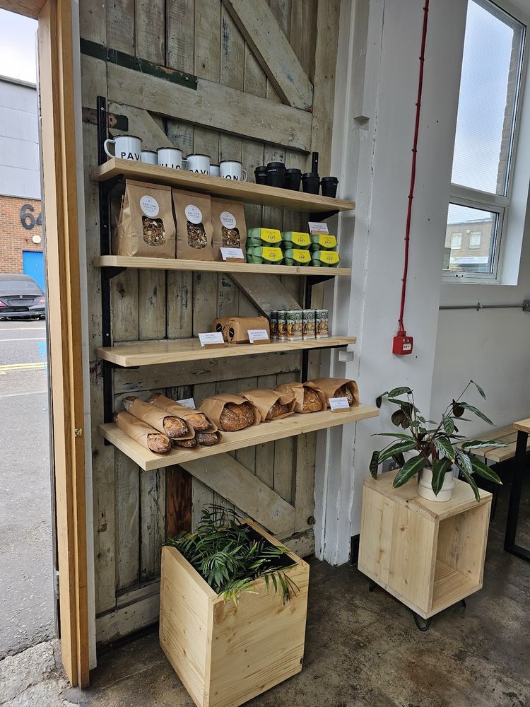 The shelving wall stocked with goods, a plant, and daylight coming through the doorway